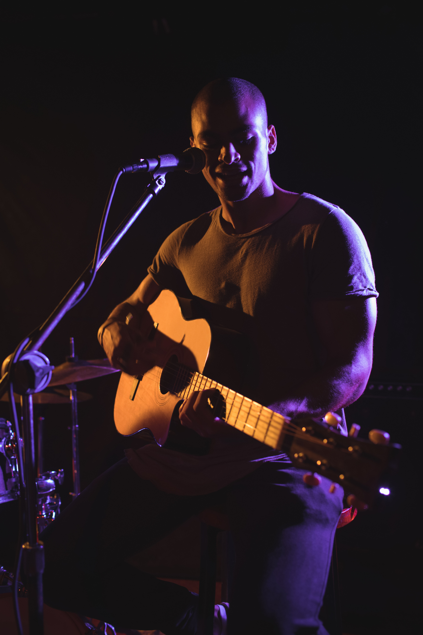 Confident male singer playing guitar in night club